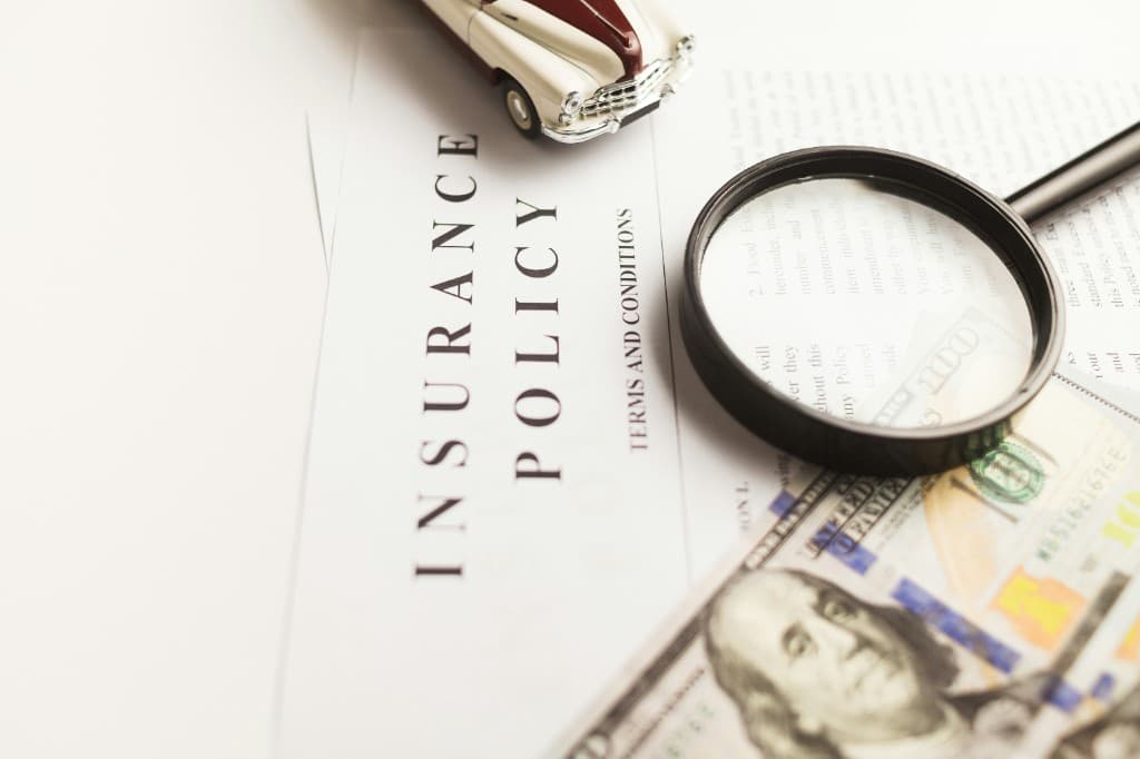 Insurance policy document with a model car and magnifying glass